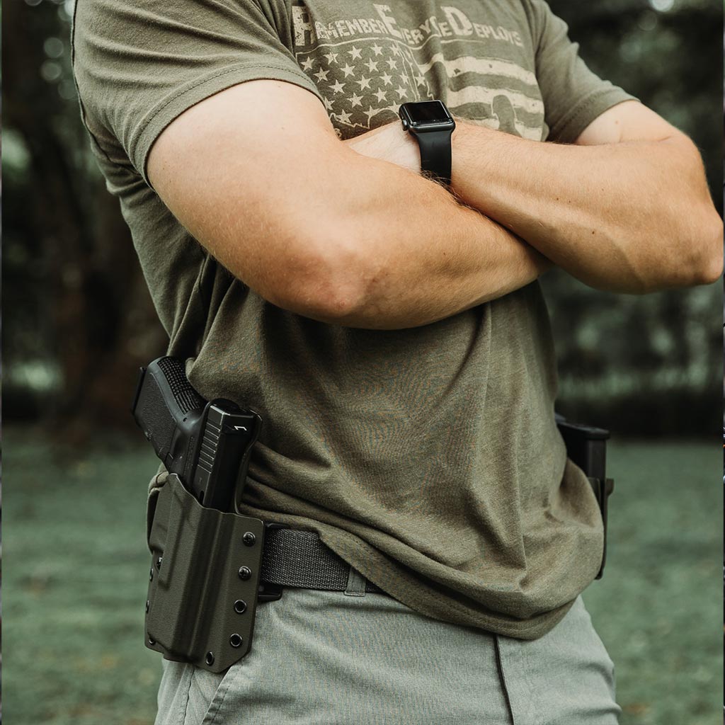 Side view of man standing with firearm holstered in a LightkDraw attached to his belt.