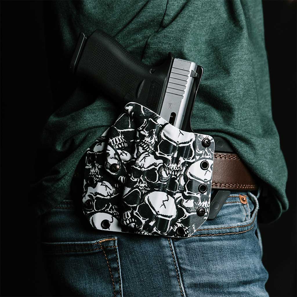 Man standing with a custom skull pattern kydex LightDraw holster attached to his belt.