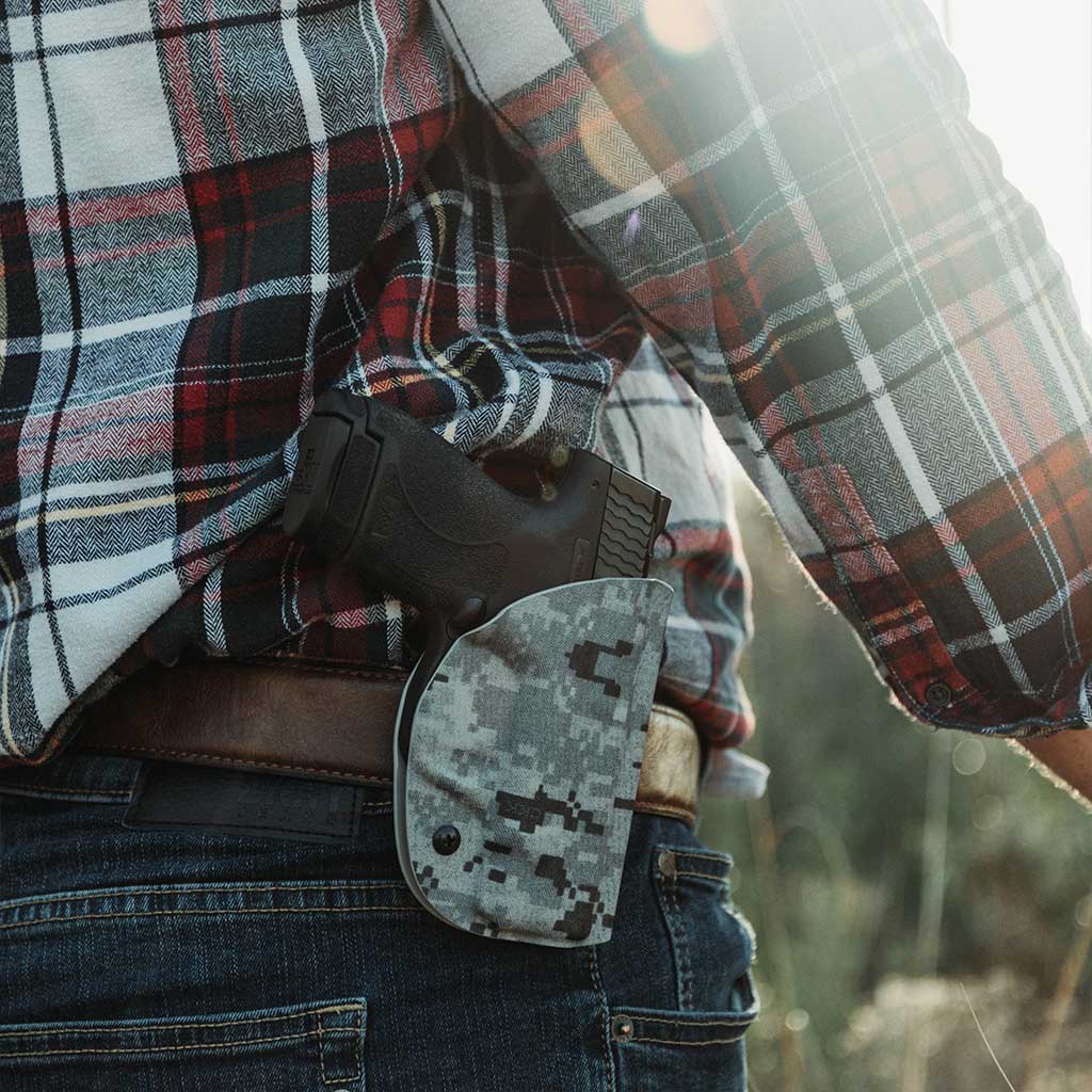 A man standing with a firearm holstered in a custom digital camo pattern Prodraw holster.