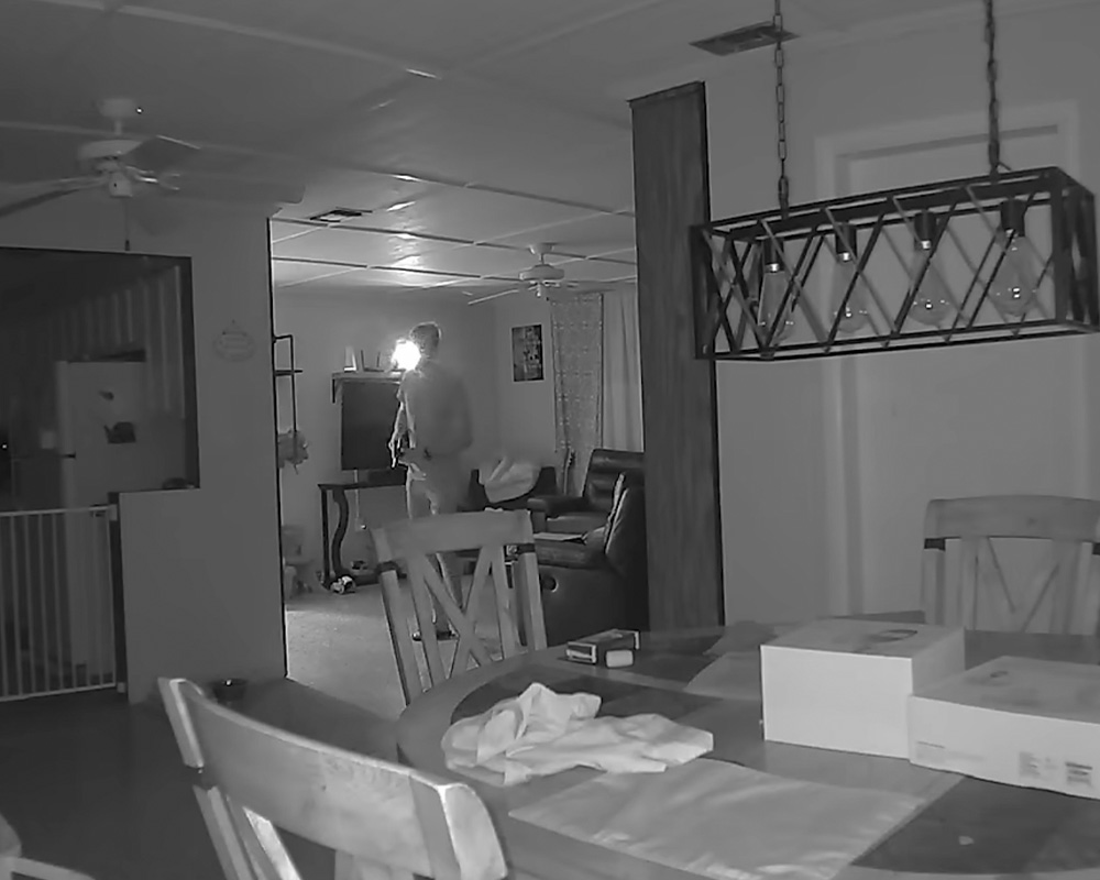 Man walking inside his apartment captured by his home camera. 