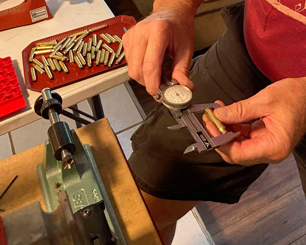 Man using tools to reload his own ammo at home.