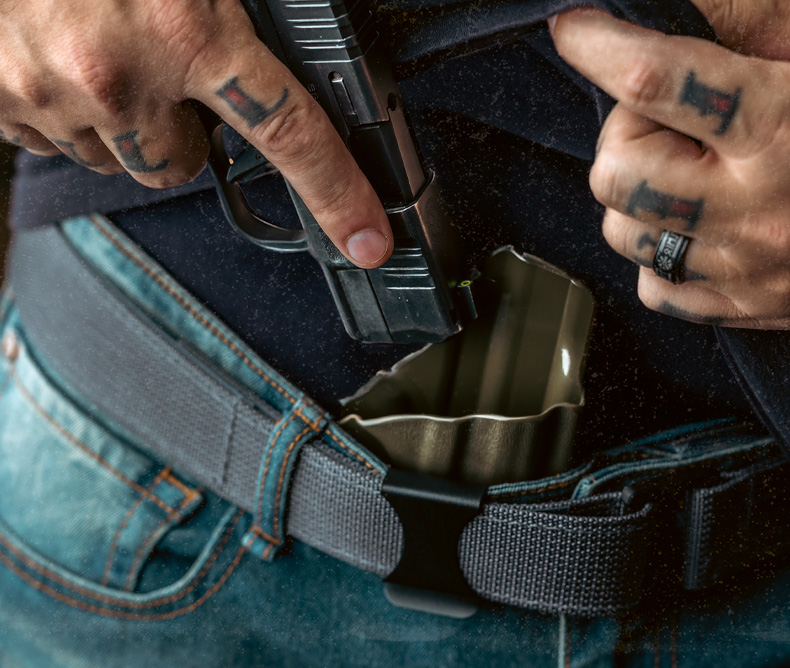 Man holstering his handgun on his Vedder Holster to conceal carry. 