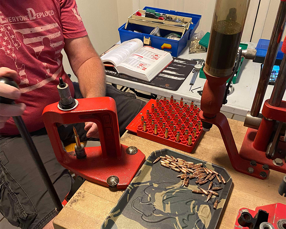 Man reloading his own ammo on small table with tools to hold the ammo, storage the powder and keep every piece on top of a Vedder Holsters EDC Tray