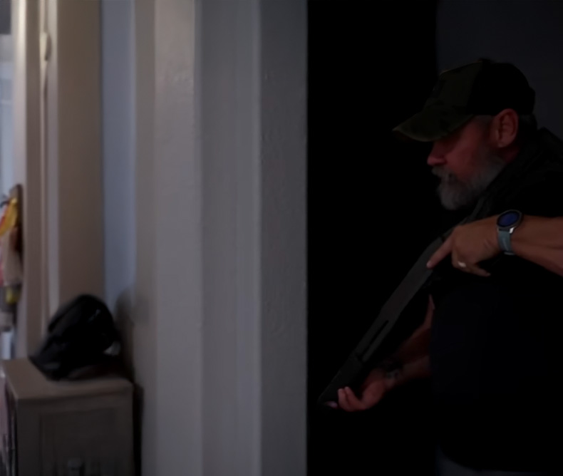 Man maneuvering around his home while holding his shotgun