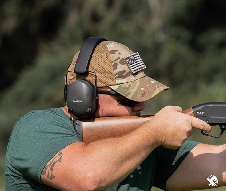  View of a man resting the comb in an optimal position while aiming his shotgun to a target in a shooting range.