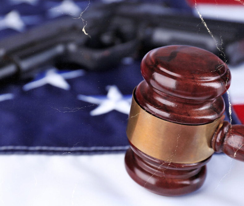 A handgun and a gavel on top of an American flag - image implies law and gun control.