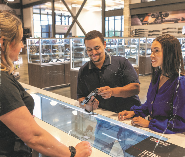 A couple checking out handguns and asking questions to the clerk assisting them with their purchase.