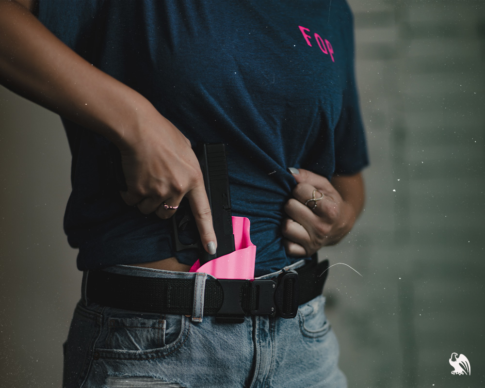 Woman pulling her gun out of her concealed carry holster