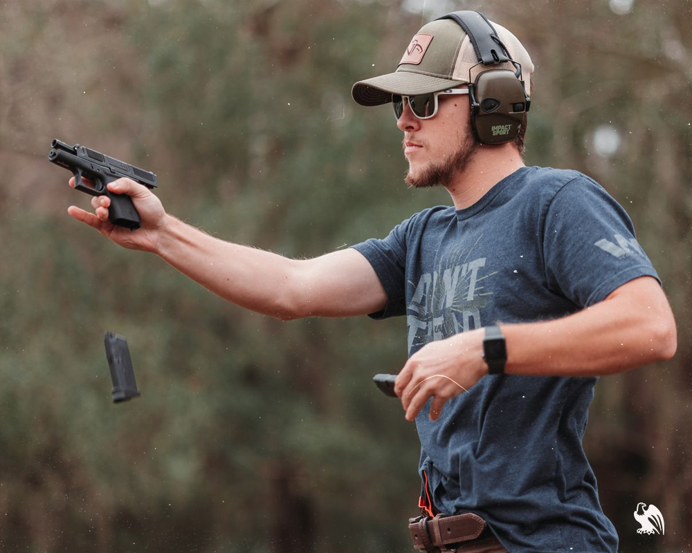 Man wearing protective ear headset at the gun range,  reloading his gun