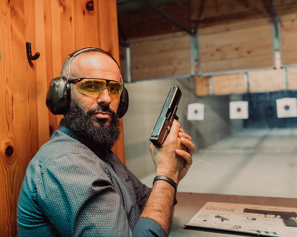 Guy looking at the camera while holding his handgun like he is ready to shoot