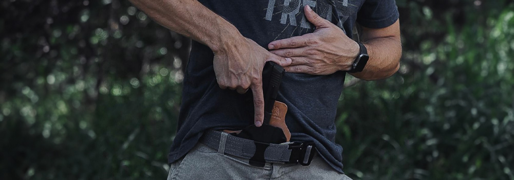 Man on the action of taking his handgun out of his holster ready for action. 