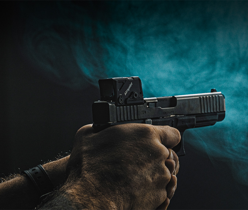 Man holding a handgun with a Glock and AIMPOINT New Red Dot Optic