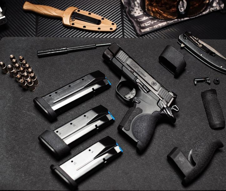 Smith & Wesson Releases New CSX E-Series Pistols, pistol is laying on a black gun cleaning mat with three magazines, bullets and knives around it.