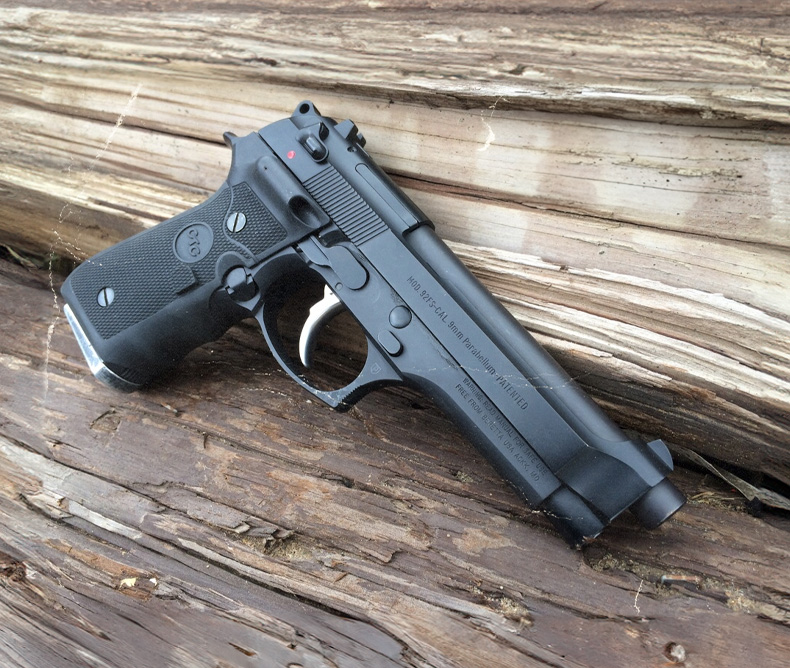 Beretta 92 handgun photography laying against wood.