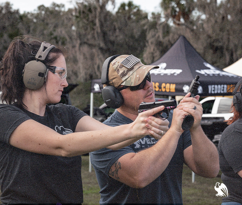 Firearms instructor teaching a female on the correct way to hold a firearm