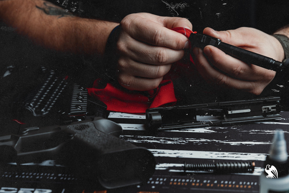 Man cleaning and greasing his handgun with gun oil